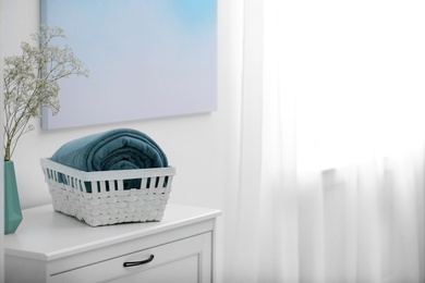 Photo of Basket with soft plaid on commode in room. Space for text