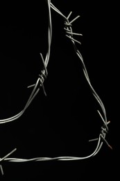 Photo of Metal barbed wire on black background, closeup