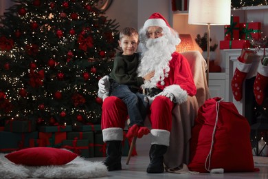 Merry Christmas. Little boy sitting on Santa's knee at home