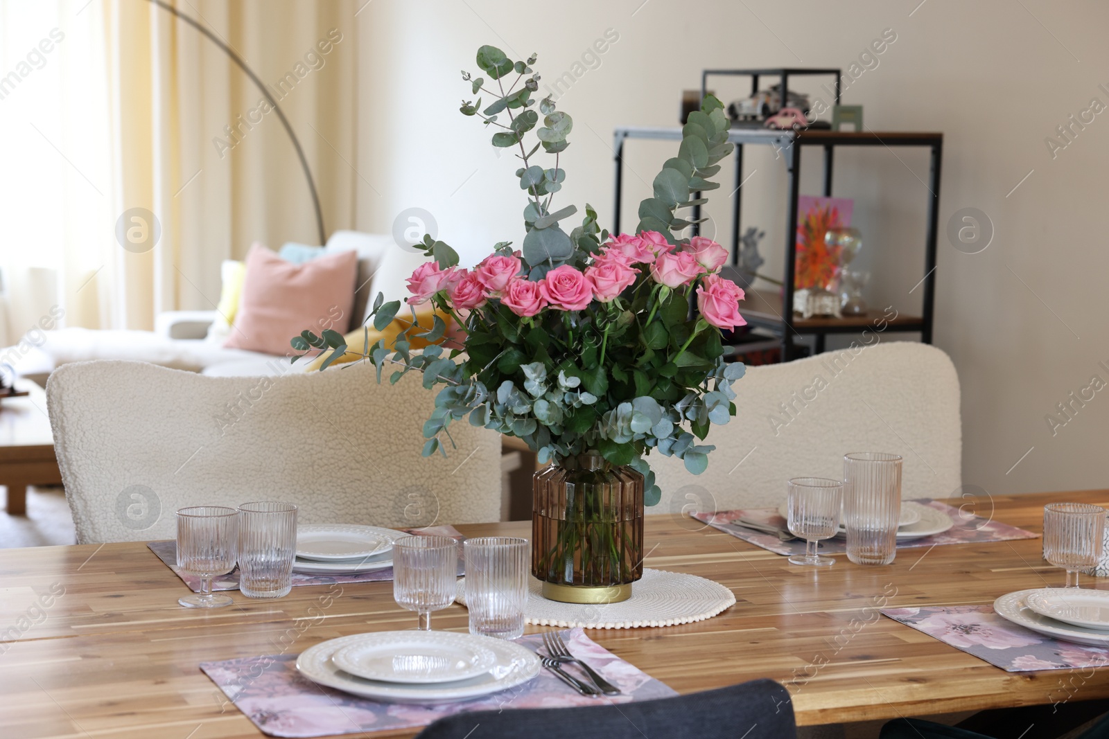 Photo of Beautiful table setting with bouquet in dining room. Roses and eucalyptus branches in vase