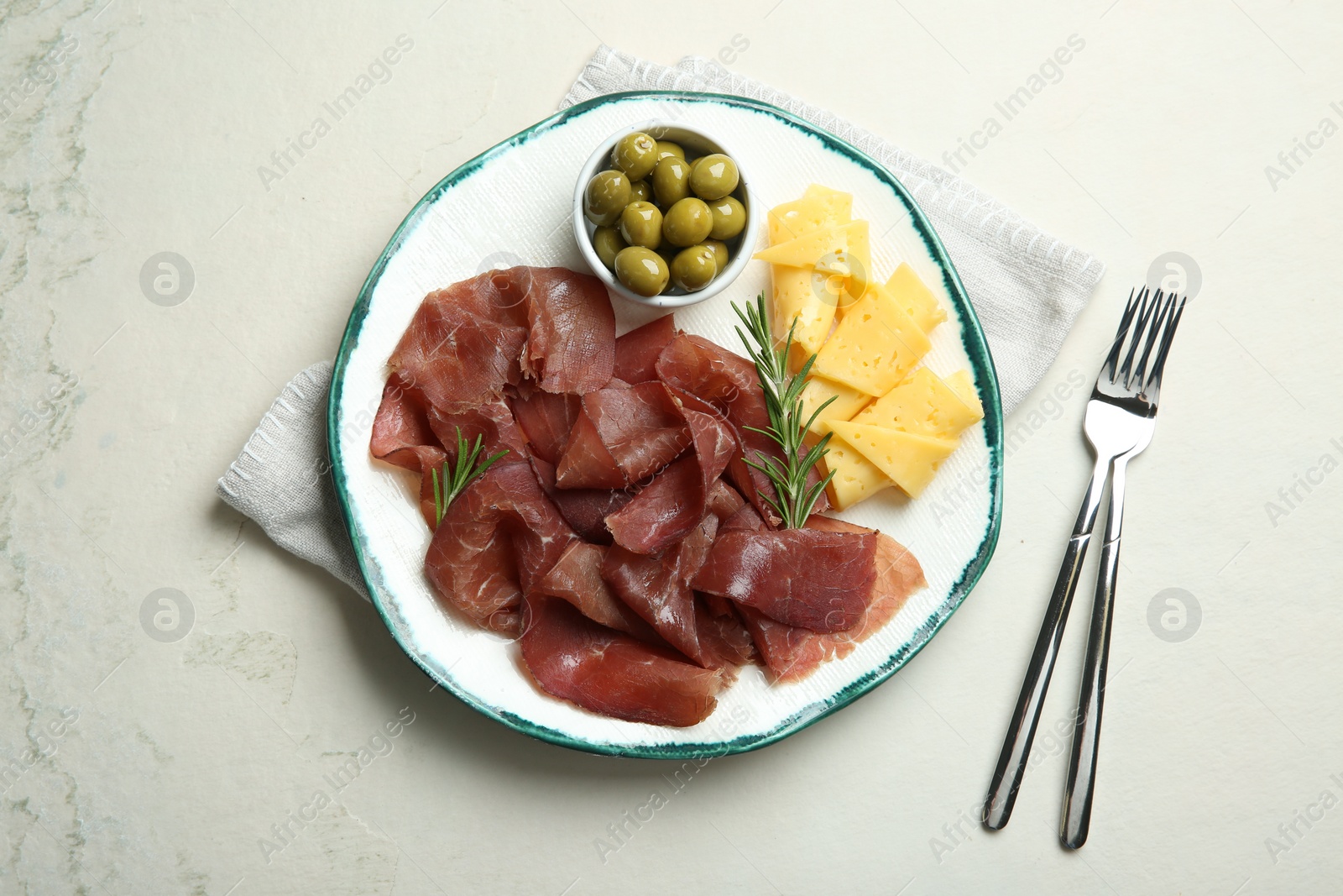Photo of Delicious bresaola, cheese, olives and rosemary served on light textured table, top view