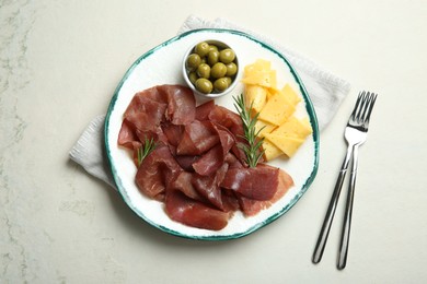 Delicious bresaola, cheese, olives and rosemary served on light textured table, top view