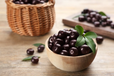 Tasty acai berries in bowl on wooden table, closeup