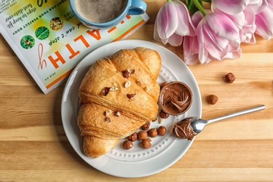 Tasty croissant with chocolate and nuts on table, top view