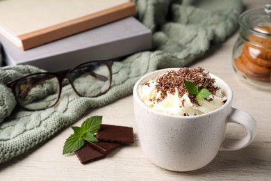 Photo of Cup of delicious hot chocolate with whipped cream and mint on white wooden table