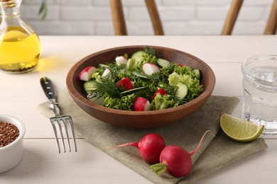 Delicious salad with radish, lettuce, dill and cucumber served on light wooden table, closeup