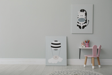 Stylish child's room interior with adorable paintings, small table and chair. Space for text