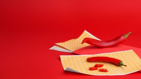 Photo of Pepper plasters and chili on red background, space for text. Alternative medicine