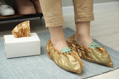 Photo of Woman wearing shoe covers onto her mules indoors, closeup