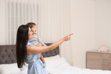 Photo of Young nanny with cute little baby in bedroom