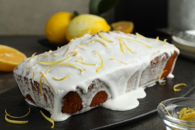 Tasty lemon cake with glaze, citrus fruits and zest on table, closeup