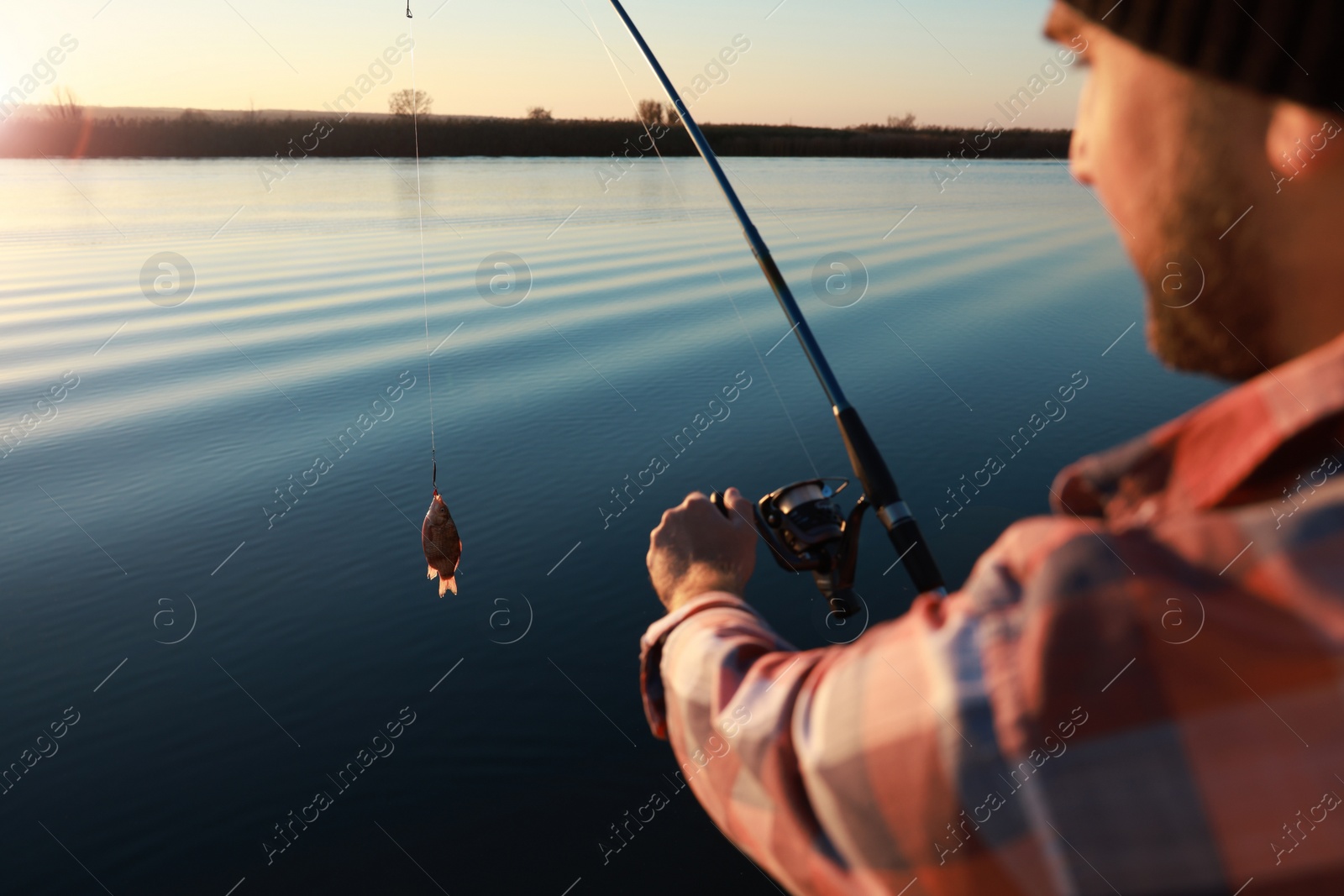 Photo of Fisherman catching fish with rod at riverside, closeup