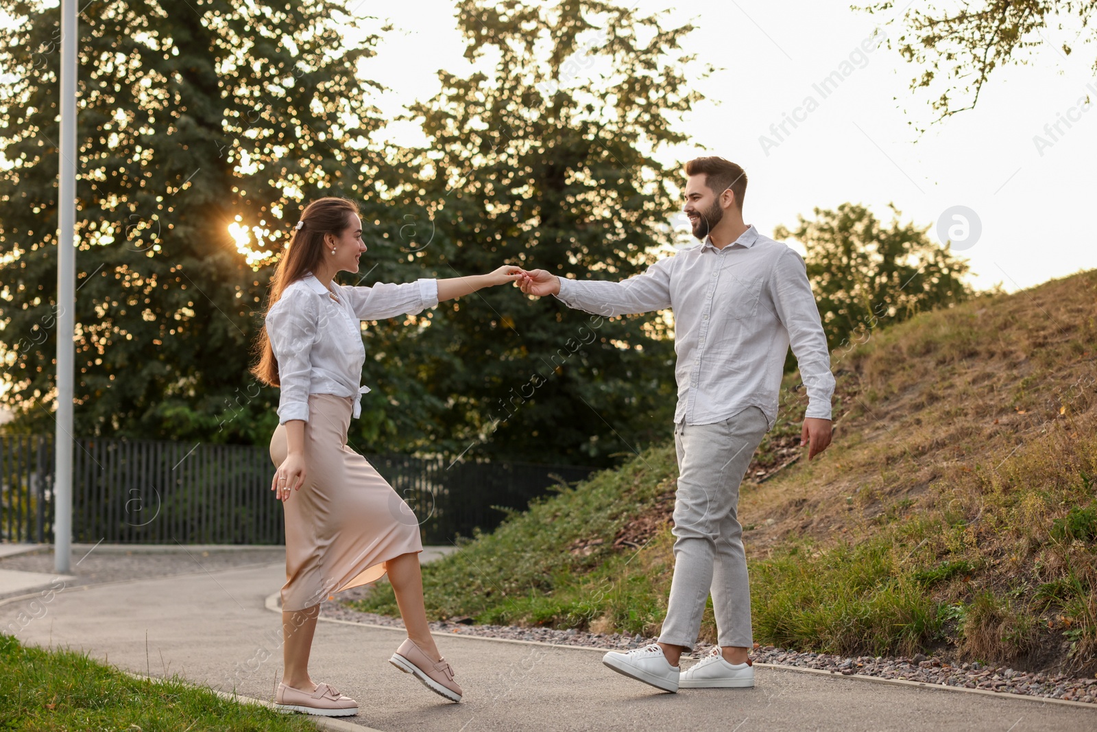 Photo of Lovely couple dancing together outdoors at sunset