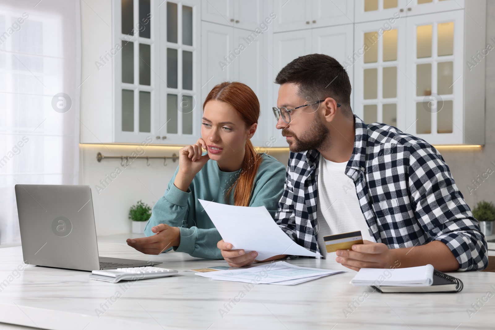 Photo of Couple with credit card using laptop for paying taxes online at home