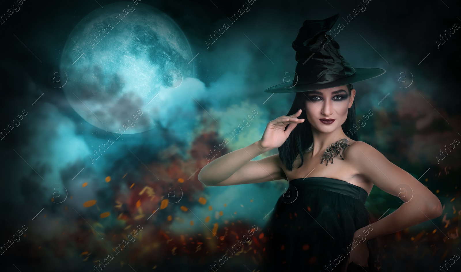 Image of Young girl dressed as witch with creepy spider on full moon night. Halloween fantasy