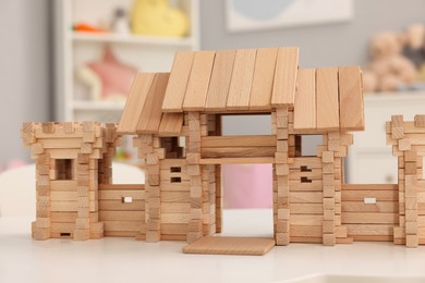 Photo of Wooden entry gate on white table indoors. Children's toy