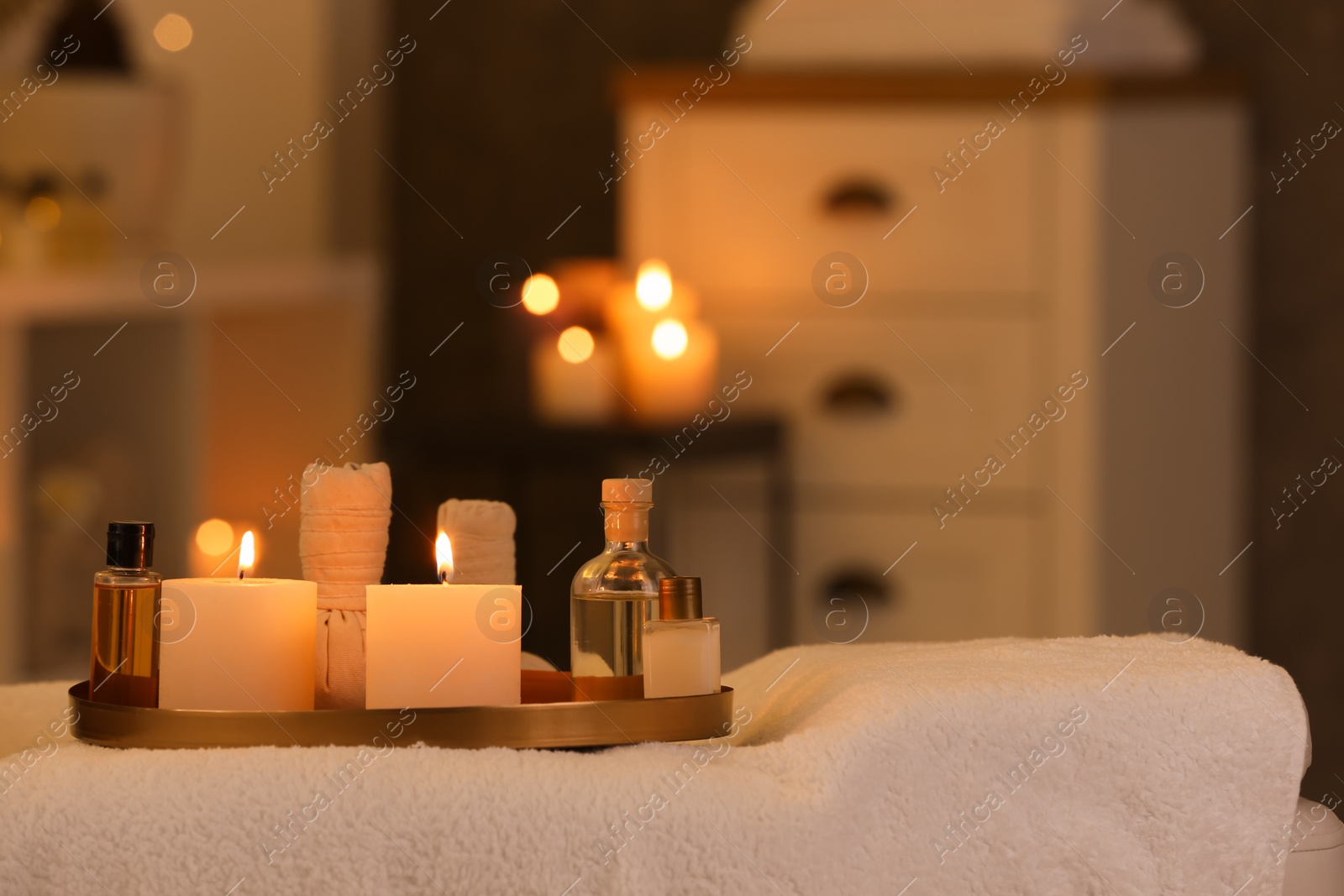 Photo of Cosmetics and burning candles on massage table in spa salon, space for text