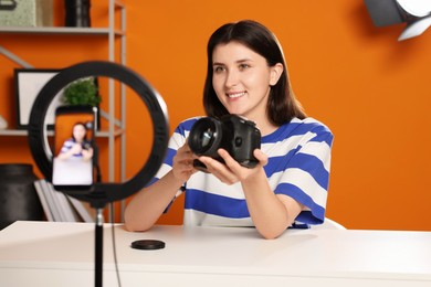 Photo of Smiling technology blogger recording video review about camera at home