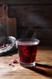 Photo of Delicious hibiscus tea in glass on wooden table. Space for text