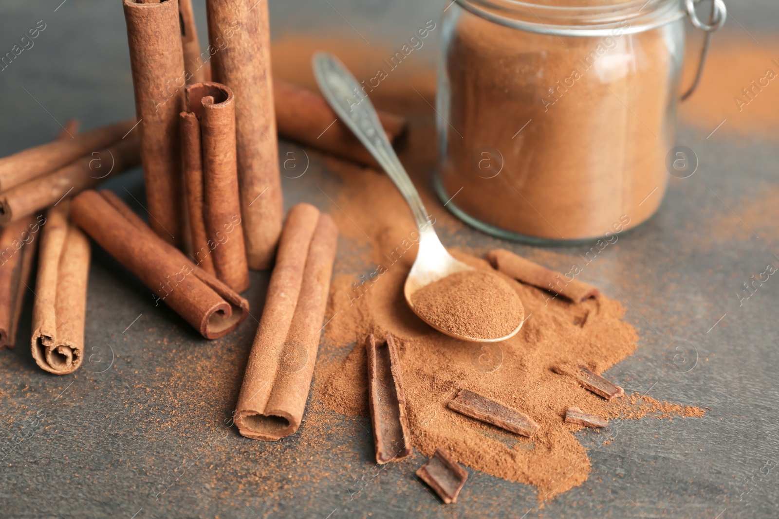 Photo of Composition with aromatic cinnamon powder and sticks on grey background