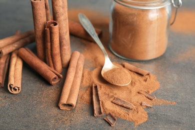 Composition with aromatic cinnamon powder and sticks on grey background