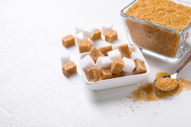 Bowls and spoon with different types of sugar on white table, closeup. Space for text