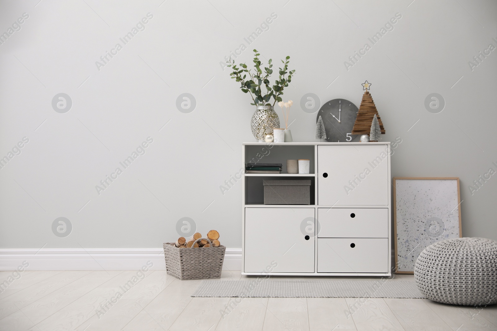 Photo of Modern room interior with white cabinet near light wall. Space for text