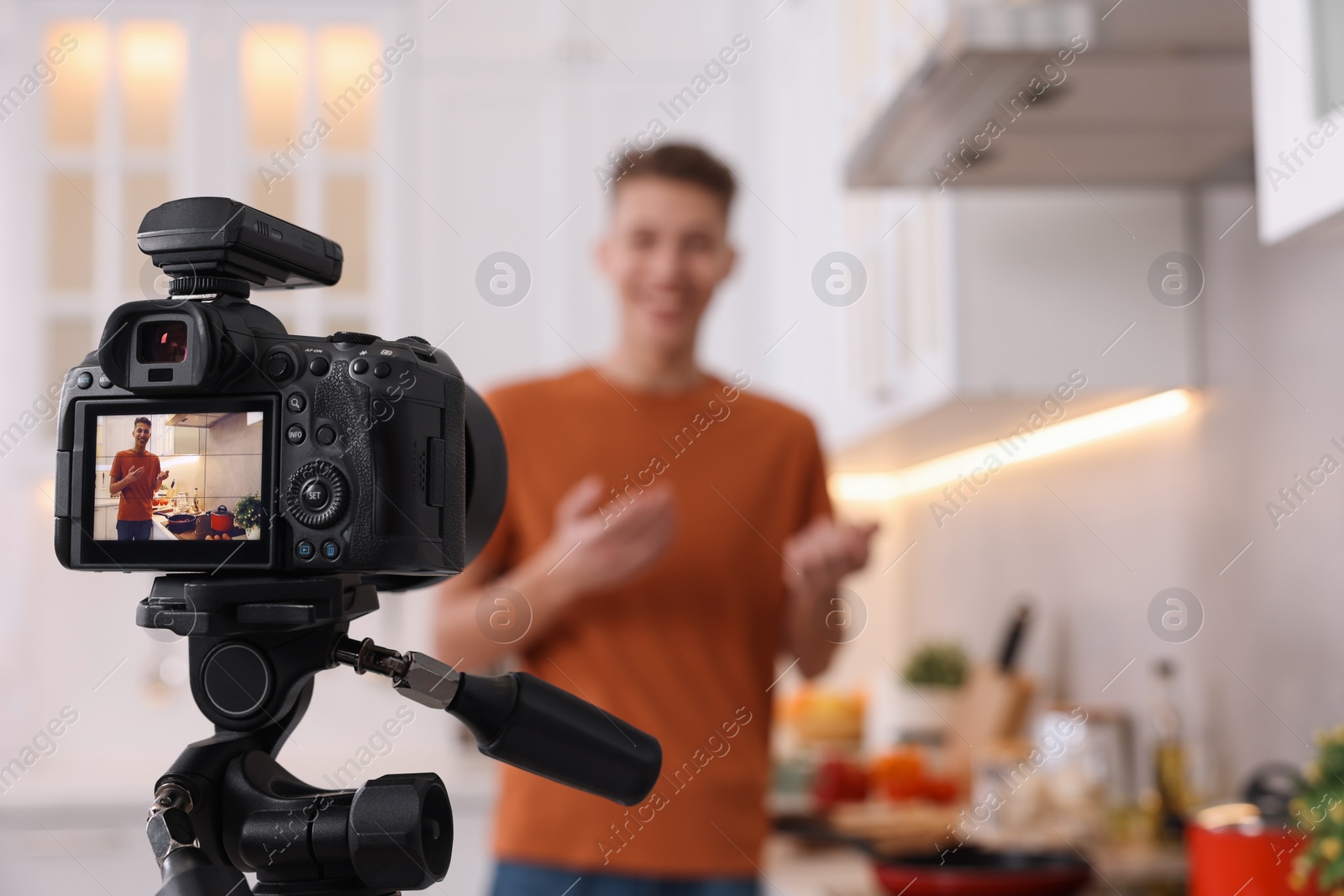 Photo of Food blogger recording video in kitchen, focus on camera