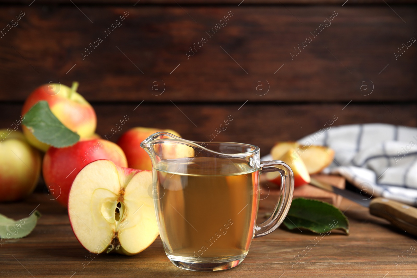 Photo of Natural apple vinegar and fresh fruits on wooden table