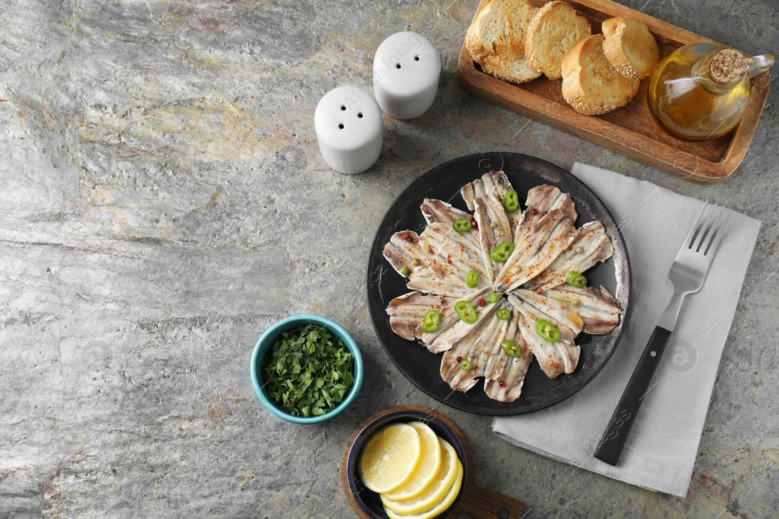 Photo of Tasty pickled anchovies served on textured table, flat lay. Space for text