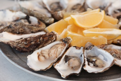 Photo of Fresh oysters with cut juicy lemon on plate, closeup