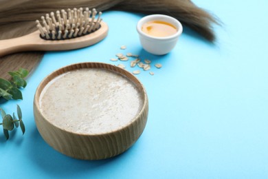Photo of Homemade hair mask, ingredients and brush on light blue background, space for text