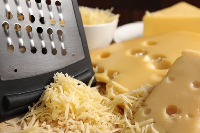 Grated, cut cheese and grater on wooden board, closeup