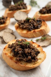 Delicious bruschettas with truffle sauce and thyme on white table, closeup