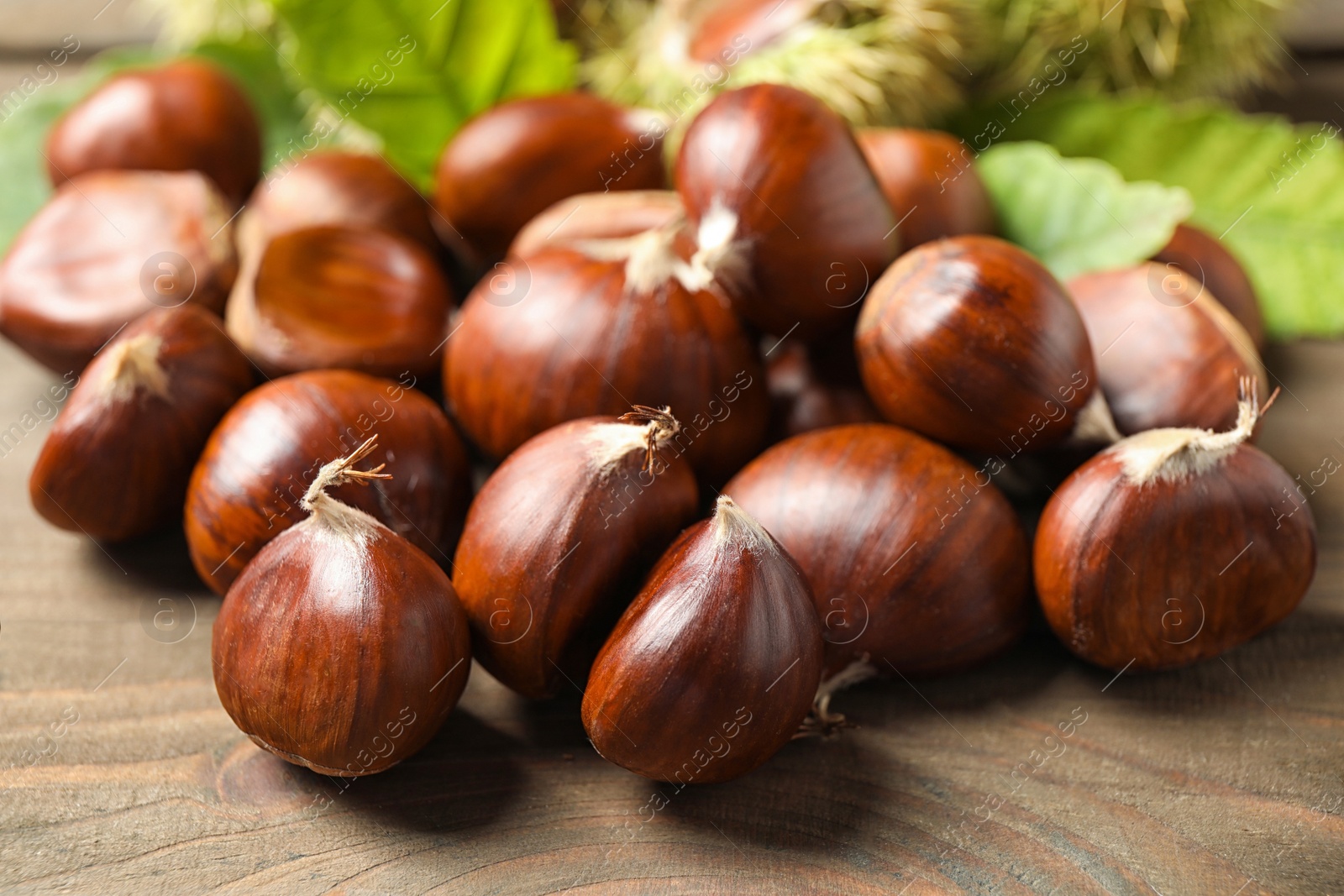 Photo of Fresh sweet edible chestnuts on wooden table, closeup