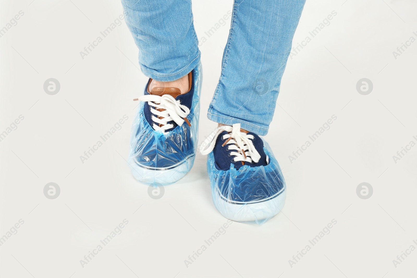 Photo of Man with blue shoe covers worn over sneakers on white background, closeup