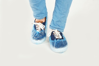 Man with blue shoe covers worn over sneakers on white background, closeup