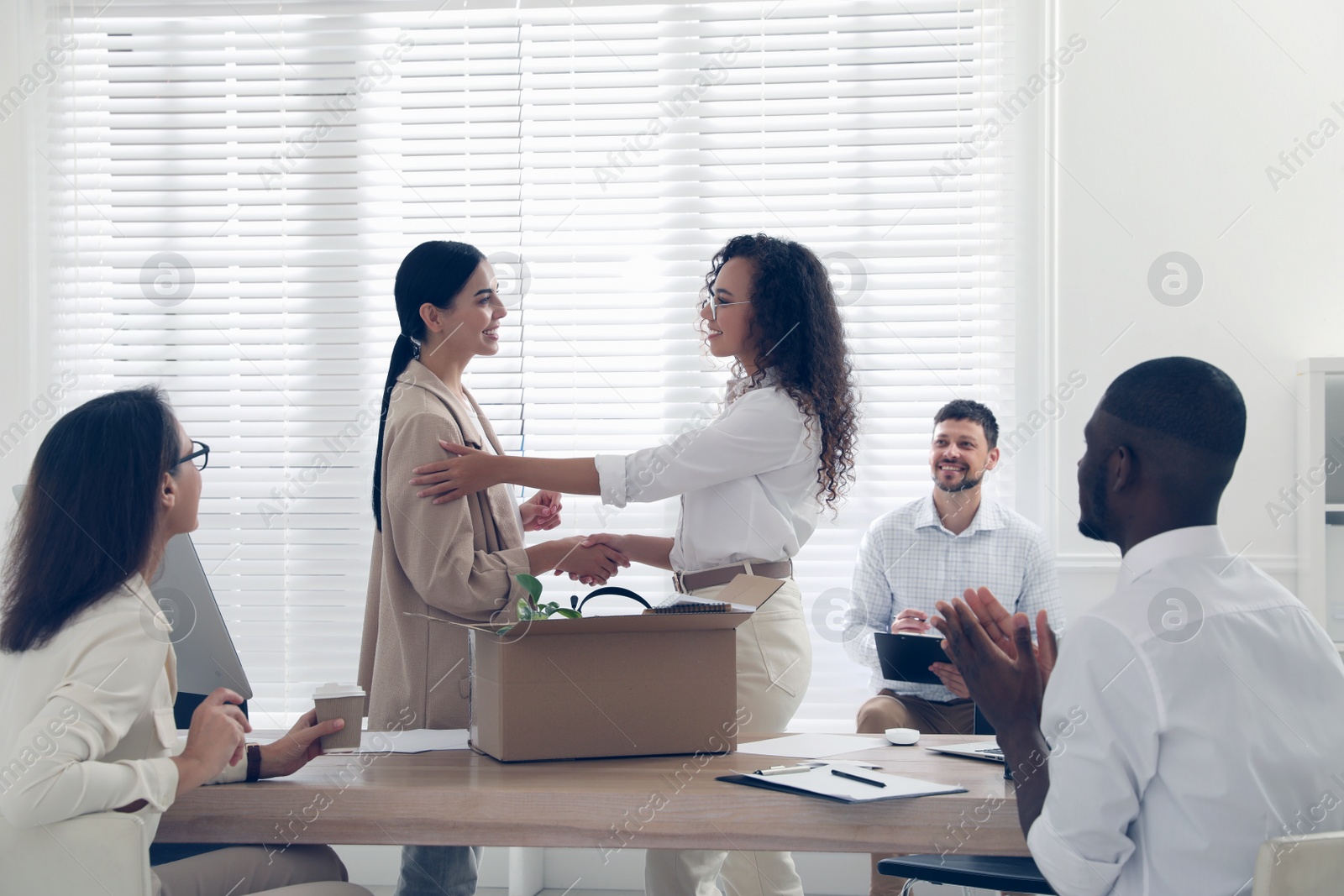 Photo of Boss shaking hand with new employee and coworkers applauding in office