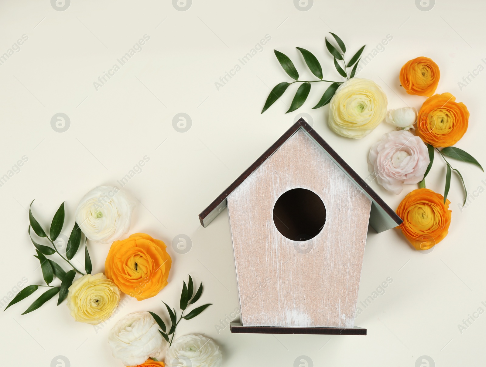 Photo of Stylish bird house and fresh flowers on beige background, flat lay