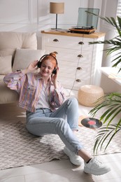 Photo of Young woman listening to music with turntable in living room