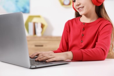 E-learning. Girl using laptop during online lesson at table indoors, closeup