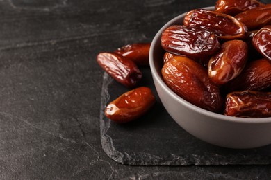 Photo of Tasty sweet dried dates on black table, closeup. Space for text