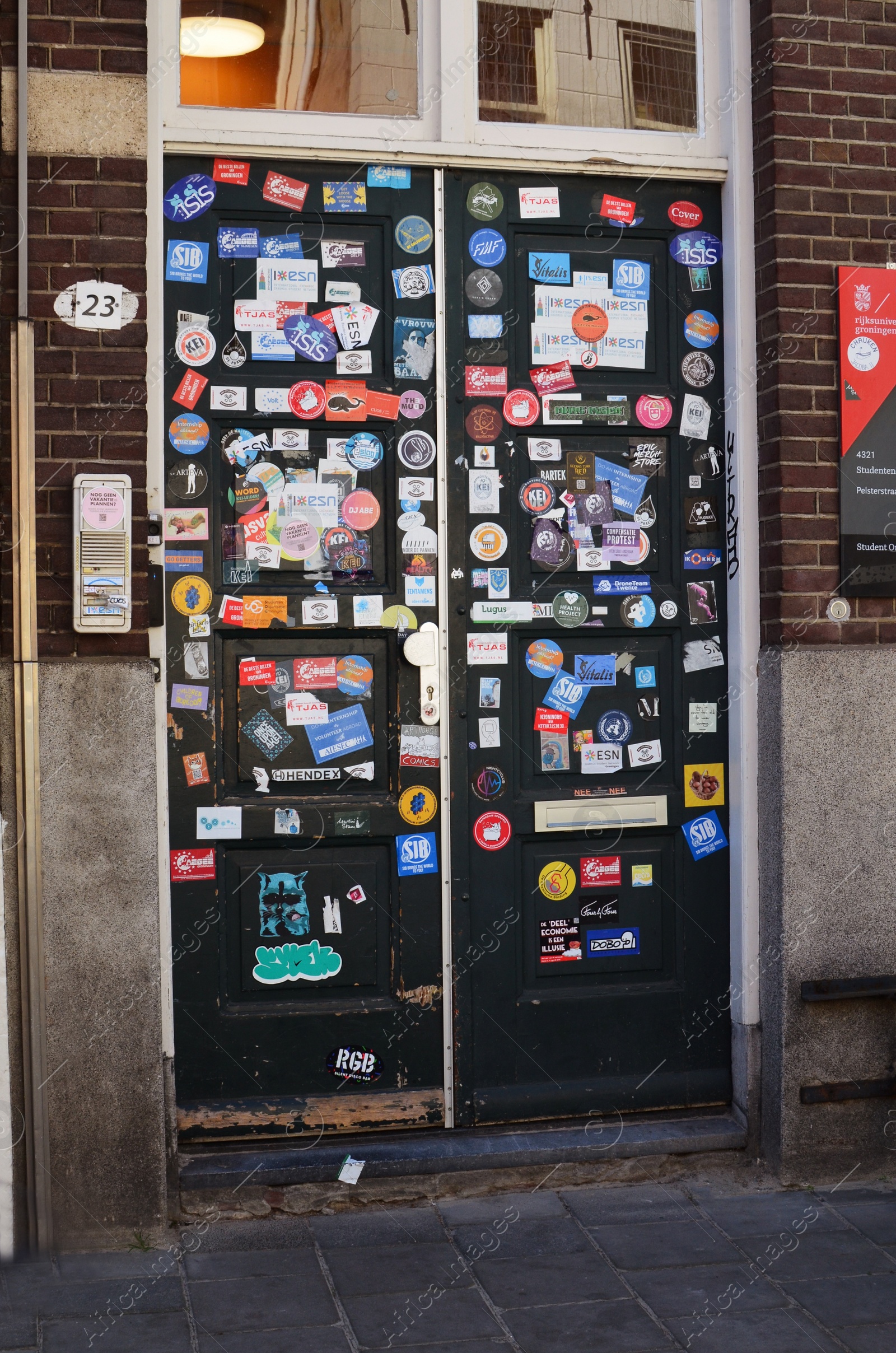 Photo of GRONINGEN, NETHERLANDS - APRIL 20, 2022: Door of modern building covered with different stickers outdoors