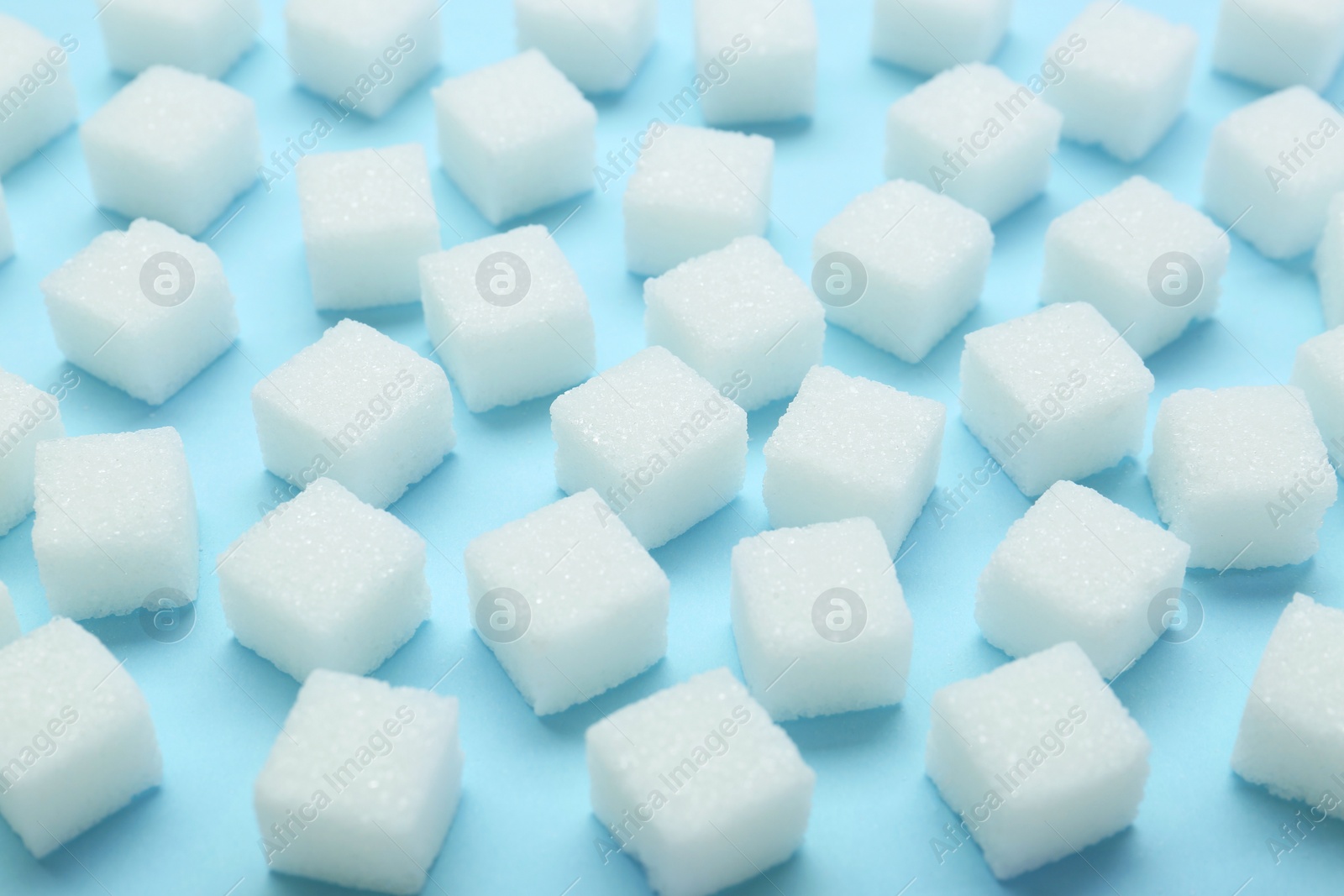 Photo of White sugar cubes on light blue background, closeup