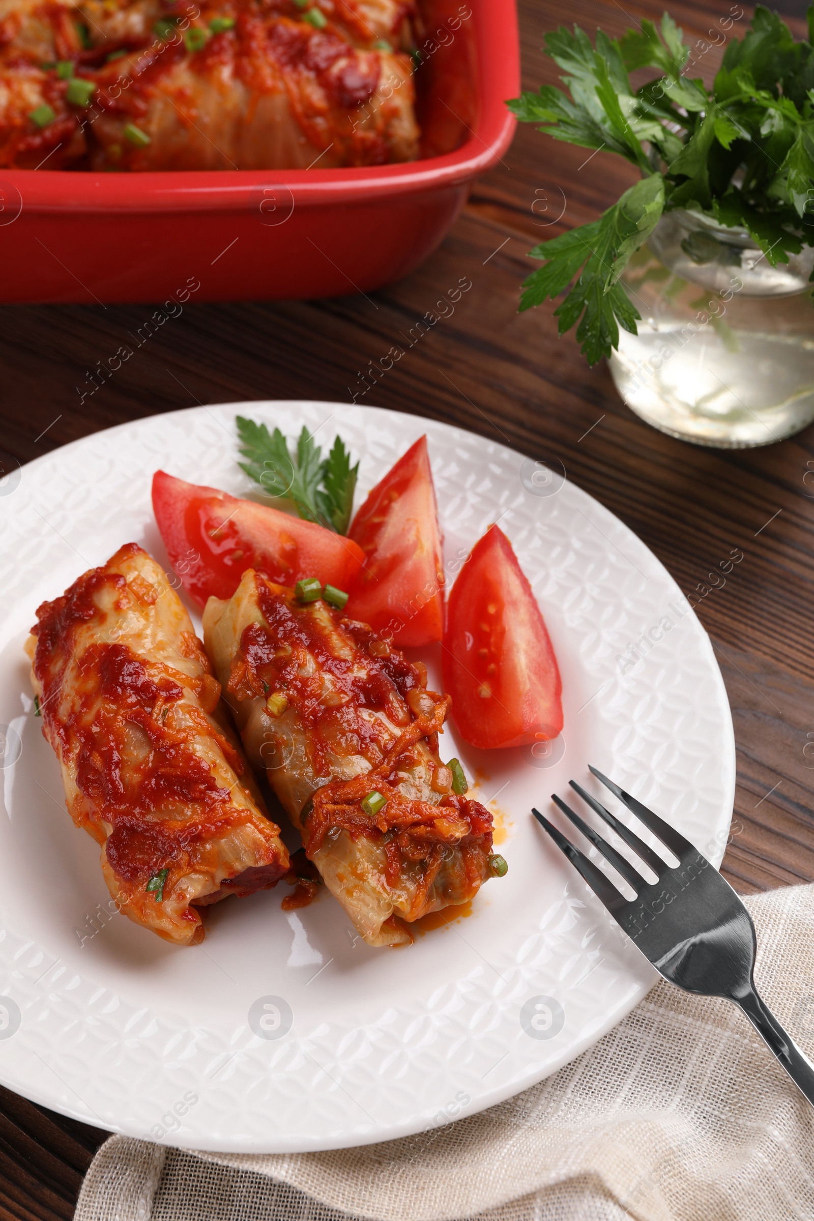 Photo of Delicious stuffed cabbage rolls with tomatoes served on wooden table, above view