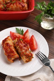 Delicious stuffed cabbage rolls with tomatoes served on wooden table, above view