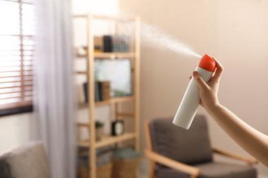 Woman spraying air freshener at home, closeup