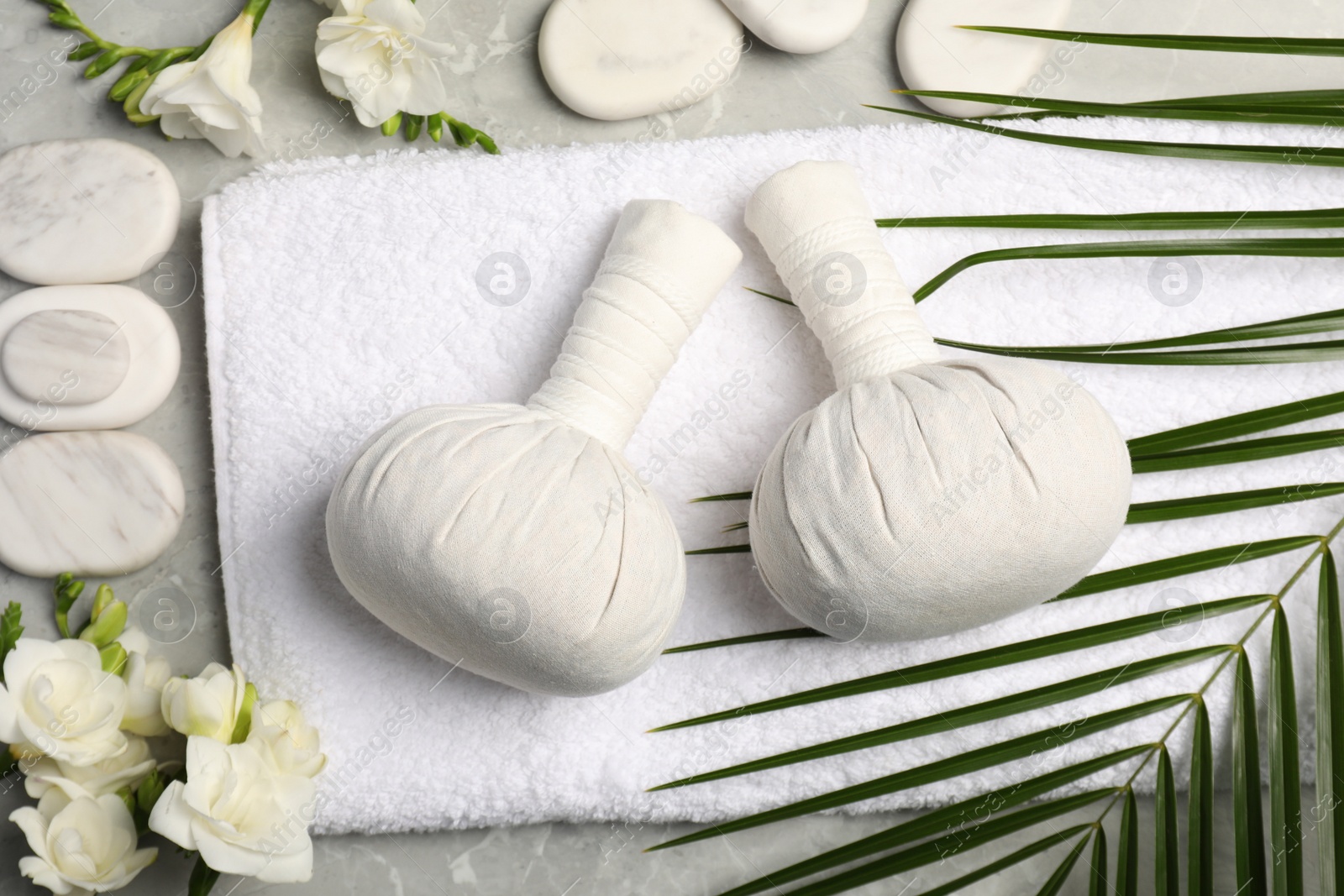 Photo of Spa bags, stones and freesia flowers on light gray marble table, flat lay