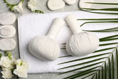 Photo of Spa bags, stones and freesia flowers on light gray marble table, flat lay