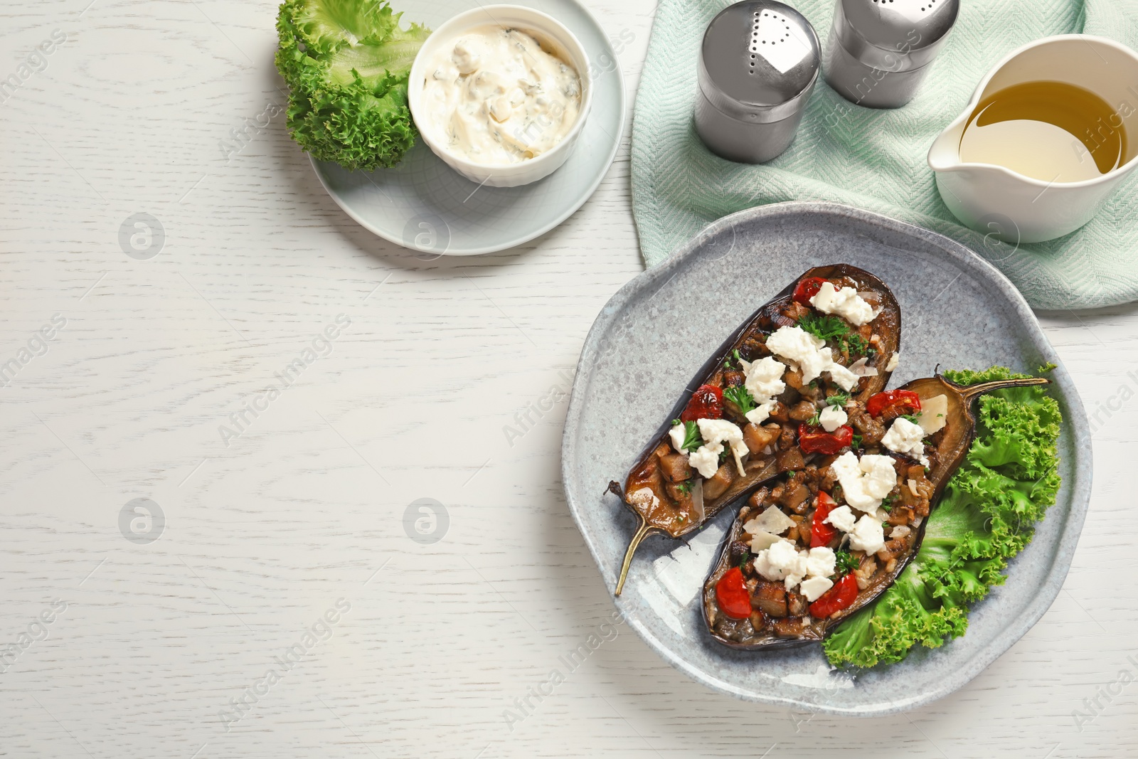 Photo of Flat lay composition with plate of stuffed eggplants and space for text on light table